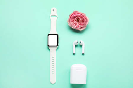 Smartwatch, earphones and peony flower on color backgroundの写真素材