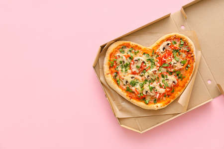 Cardboard box with tasty heart-shaped pizza on pink background. Valentine's Day celebrationの写真素材