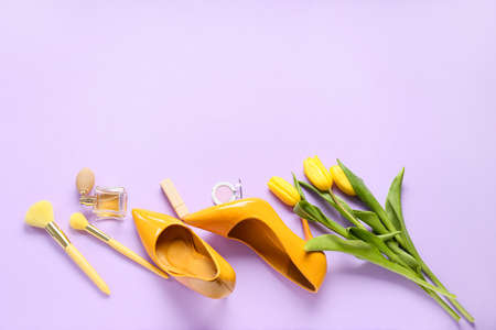 Female shoes, makeup brushes, perfume and flowers for International Women's Day celebration on purple backgroundの写真素材