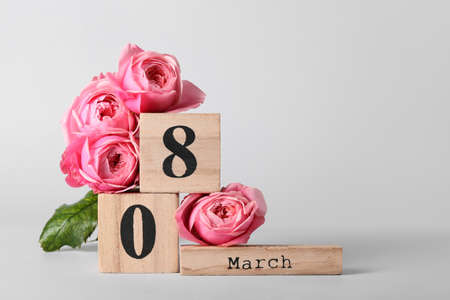 Calendar and flowers for International Women's Day celebration on light background