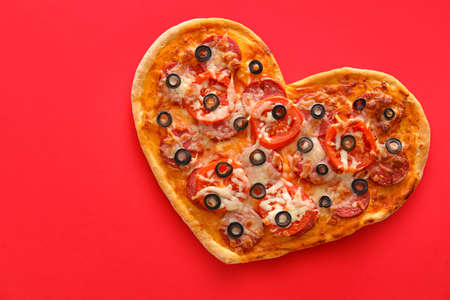 Tasty heart-shaped pizza on red background. Valentine's Day celebrationの写真素材