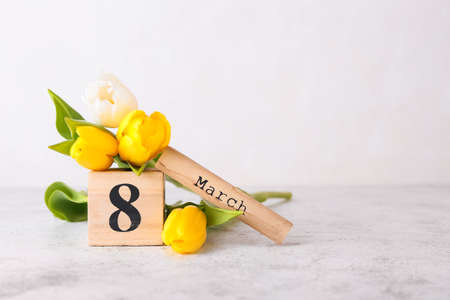 Calendar and flowers for International Women's Day celebration on light background