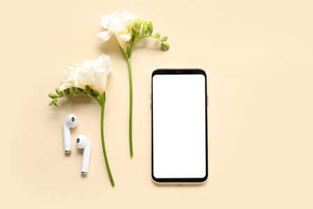 Mobile phone, earphones and beautiful flowers on color backgroundの写真素材