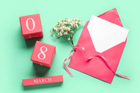 Cube calendar with date MARCH 8, opened envelope and gypsophila flowers for International Women's Day celebration on color backgroundの写真素材