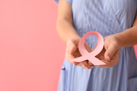 Woman with pink awareness ribbon on color background, closeup. breast cancer awareness conceptの写真素材
