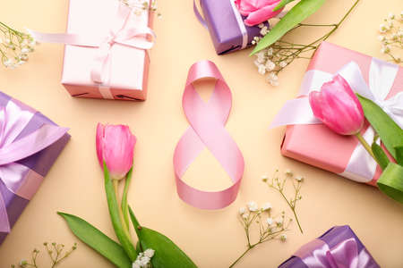 Composition with figure 8 made of ribbon, gift boxes and flowers for International Women's Day celebration on color backgroundの写真素材