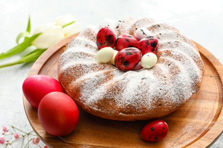 Plate with tasty Easter cake and eggs on light background