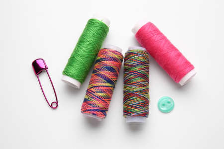 Thread spools with button and pin on white background