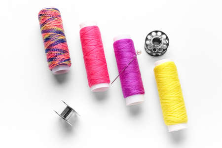 Thread spools and needles on white background