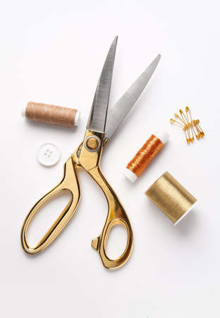 Thread spools with scissors, button and pins on white backgroundの写真素材