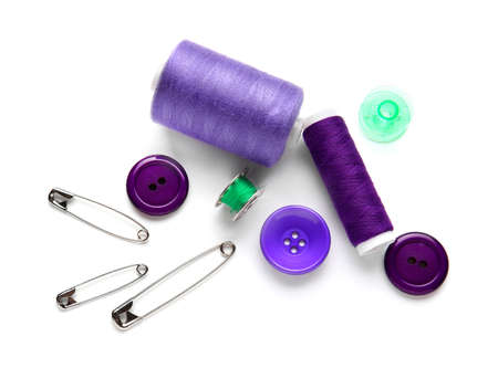Thread spools with buttons and pins on white background