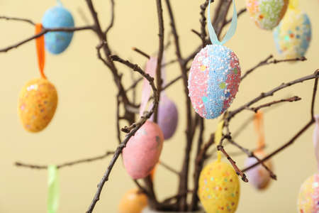 Composition with different Easter eggs hanging on tree branches against color background, closeupの写真素材