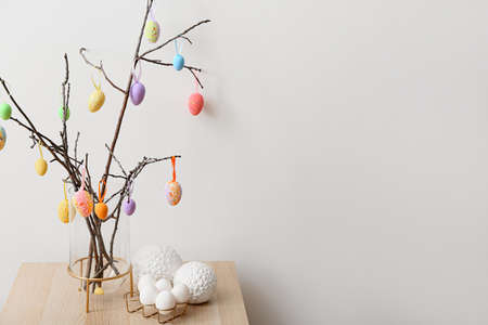Tree branches with different Easter eggs and stylish decor on wooden table