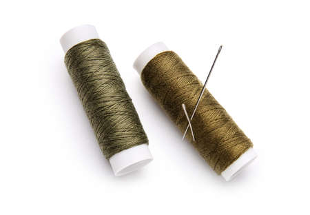 Thread spools with needles on white background