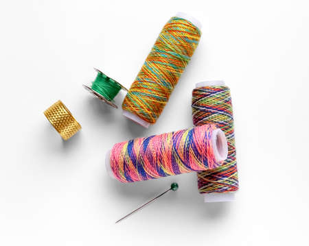 Thread spools and needles on white background