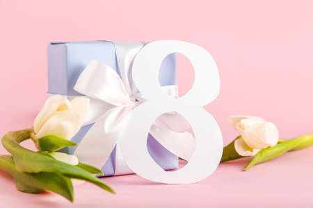Greeting card for International Women's Day celebration with paper figure 8, gift box and tulips on...