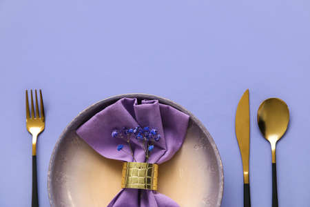 Elegant table setting and flowers on purple background