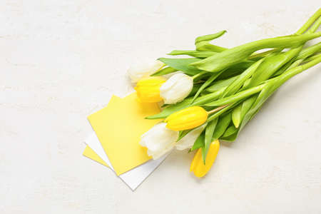 Blank greeting card for International Women's Day and bouquet of tulips on light background
