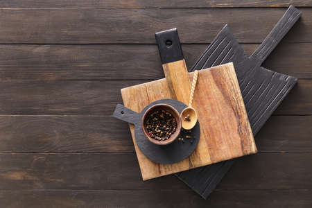 Cutting boards and bowl with peppercorn on dark wooden background