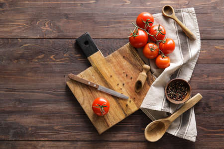 Cutting board, knife, peppercorn and tomatoes on wooden backgroundの写真素材