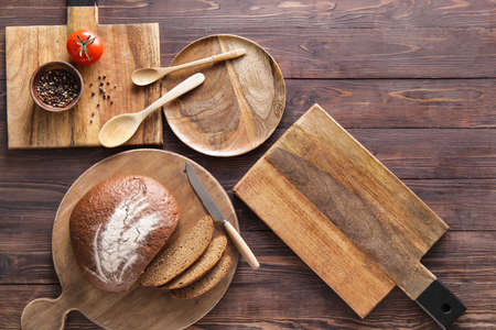 Cutting boards, plate, spoons and bread on wooden background