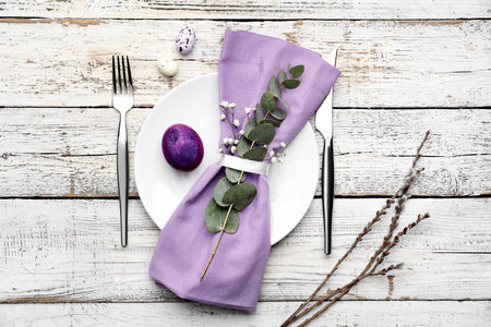 Stylish table setting for Easter celebration on light wooden background
