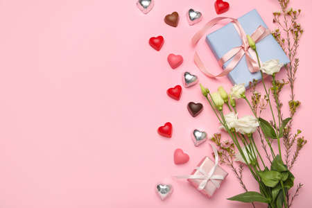Composition with tasty heart-shaped candies and flowers for Valentine's Day celebration on pink backgroundの写真素材
