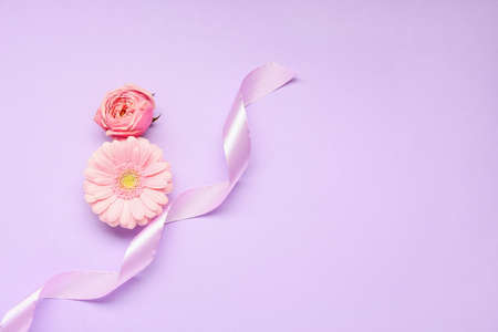 Composition with beautiful flowers and ribbon on color background. International Women's Day celebrationの写真素材