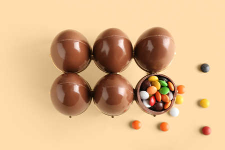 Holder with chocolate Easter eggs and candies on beige backgroundの写真素材