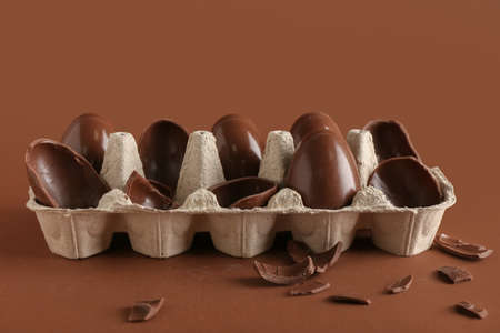 Holder with broken chocolate Easter eggs on brown backgroundの写真素材
