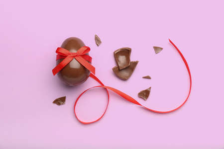 Composition with broken chocolate Easter egg on pink backgroundの写真素材