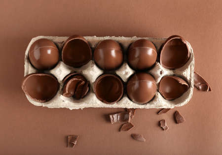 Holder with broken chocolate Easter eggs on brown background