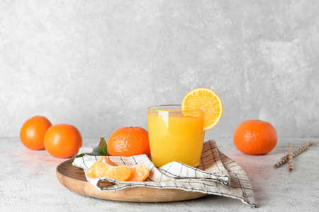Glass of fresh tangerine juice on light backgroundの写真素材