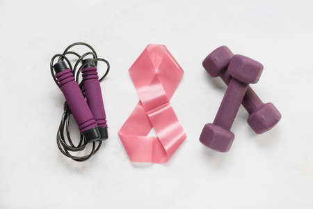 Composition with skipping rope, elastic band and dumbbells on light background. International...
