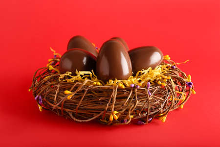 Nest with chocolate Easter eggs on red background, closeupの写真素材