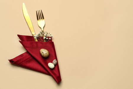 Stylish Easter cutlery on beige background