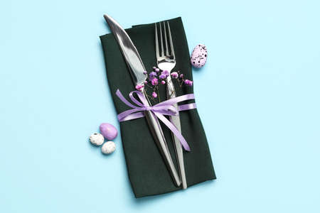 Stylish Easter cutlery on blue background