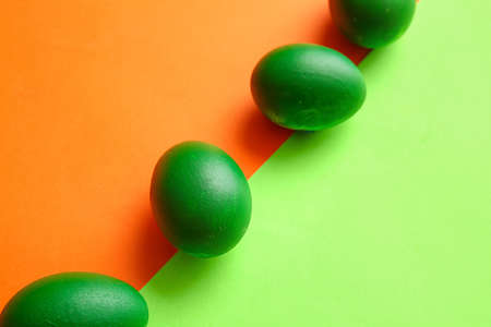 Green painted Easter eggs on color background