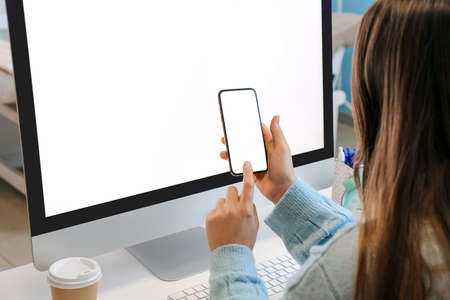 Woman using mobile phone on table with modern computerの写真素材