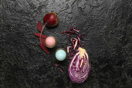 Holders with beautiful Easter eggs, purple cabbage and beet on dark backgroundの写真素材