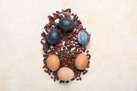 Composition with homemade dyed Easter eggs, coffee beans and dried hibiscus on light backgroundの写真素材