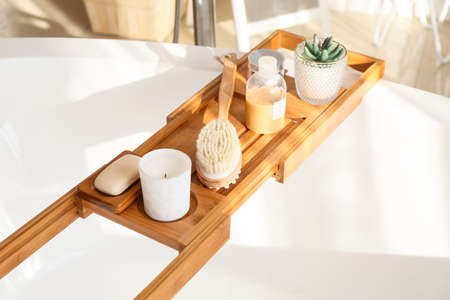 Bathtub tray with body massage brush, candle and cosmetic productsの写真素材