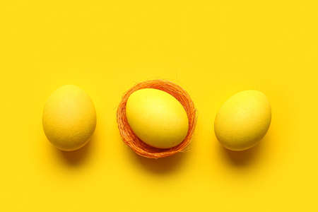 Yellow painted Easter eggs on color backgroundの写真素材
