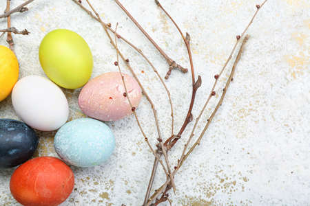 Composition with beautiful Easter eggs and tree branches on light background, closeupの写真素材