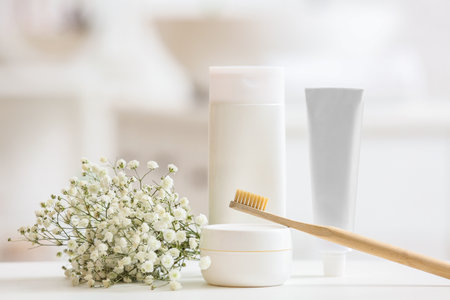 Toothbrush, cosmetic products and gypsophila flowers on table, closeup