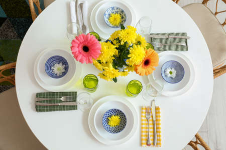 Dining table with stylish setting and beautiful flowers