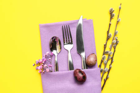 Beautiful cutlery for Easter celebration on yellow background