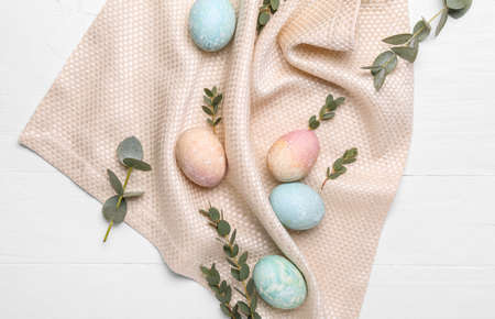 Painted Easter eggs, eucalyptus branches and napkin on white wooden backgroundの写真素材