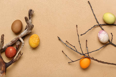 Multicolored Easter eggs and tree branches on light background