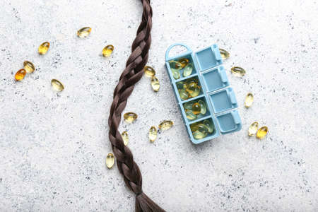 Container with pills and hair strand on grunge backgroundの写真素材